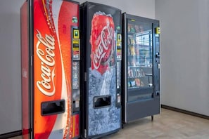 Tre försäljningsautomater med Coca-Cola-produkter står uppställda i en korridor.