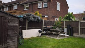 A backyard with a wooden fence, a barbecue grill, a bicycle, and a shed. - Small Cozy Room in Chelmsford Springfield (Springfield)