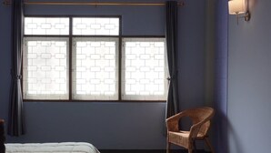 Une chambre à coucher comprenant un lit, une chaise, une fenêtre avec des rideaux et un appareil de climatisation.