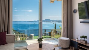 A room with a large sliding glass door leading to a balcony with a view of the sea and mountains. - Aithra Seaview Suite by Konnect (Barbati)
