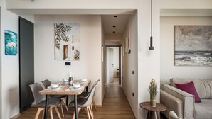 A modern interior with a dining area, a sofa, and artwork on the walls. - Aithra Seaview Suite by Konnect (Barbati)