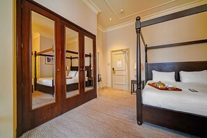 Una habitación de hotel con cama con dosel, un espejo grande y suelo alfombrado.