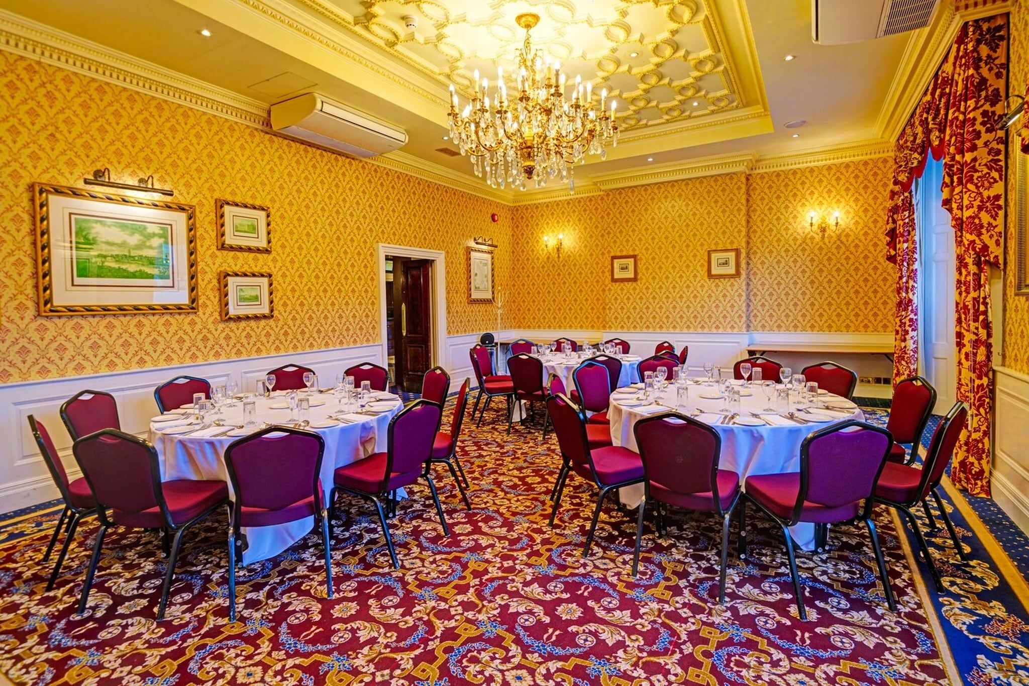 A conference room with round tables, red chairs, and a patterned carpet.