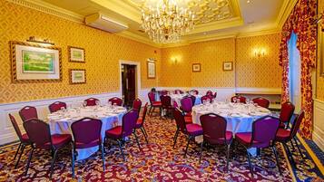 A conference room with round tables, red chairs, and a patterned carpet.