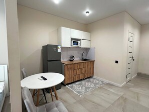 A compact kitchen with a refrigerator, microwave, sink, and wooden cabinets.