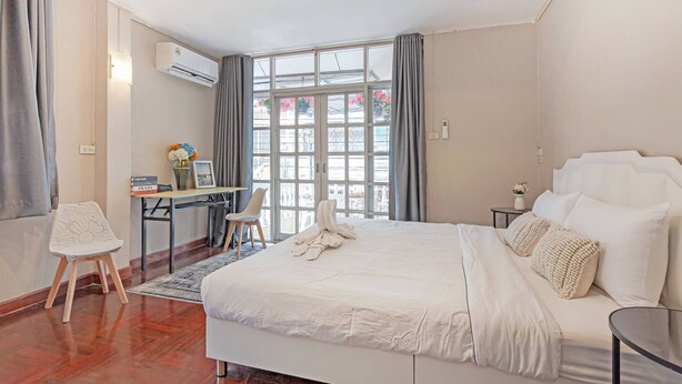 A hotel room with a large bed, a desk with a chair, and a view through a window.