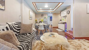 A living room with a sofa, ottoman, and a dining area with chairs and a table.