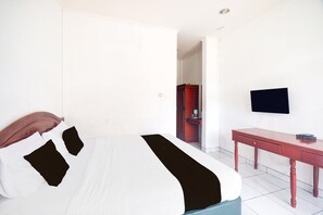 A hotel room with a bed, a desk, and a television. - Luxury Family Suite W/ Free Wifi Parking and Pool (Cisarua)