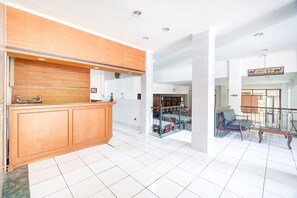 A reception area with a wooden counter, a staircase with a metal railing, and a seating area with a chair. - Luxury Family Suite W/ Free Wifi Parking and Pool (Cisarua)