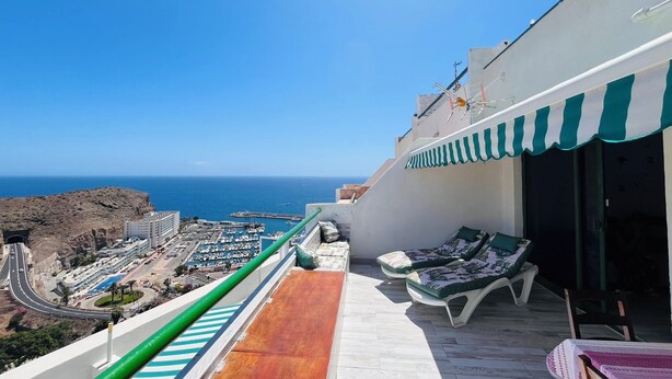 Ein Balkon mit Meerblick, ein Stuhl und ein Tisch.
