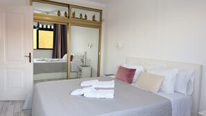 Ein Hotelzimmer mit Bett, Kleiderschrank, Nachttisch und Spiegel.