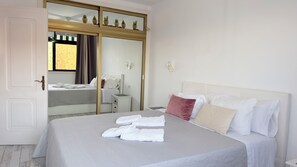 Ein Hotelzimmer mit Bett, Kleiderschrank, Nachttisch und Spiegel.