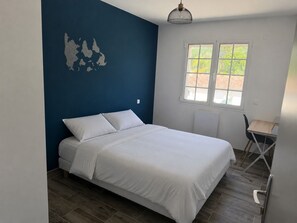 Un dormitorio con cama, ventana y sillón.