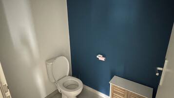 A bathroom with a toilet, a cabinet, and a blue wall.