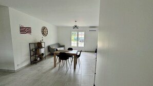 Ein geräumiges Zimmer mit Esstisch, Stühlen, einer Couch, einem Bücherregal und einer Flagge an der Wand.
