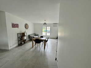 Una habitación amplia con una mesa de comedor, sillas, un sofá, una estantería y una bandera en la pared.