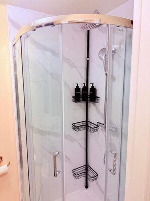 A glass-enclosed shower stall with a curved door, a hand dryer, and a showerhead. - Charming 4-Bedroom Holiday Home in  Chorley (Chorley)