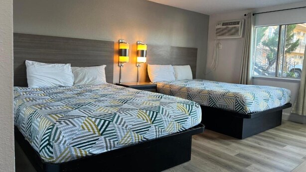 Hotellihuone, jossa on kaksi sänkyä, seinään kiinnitetty puhelin ja ikkuna, josta on näkymä.