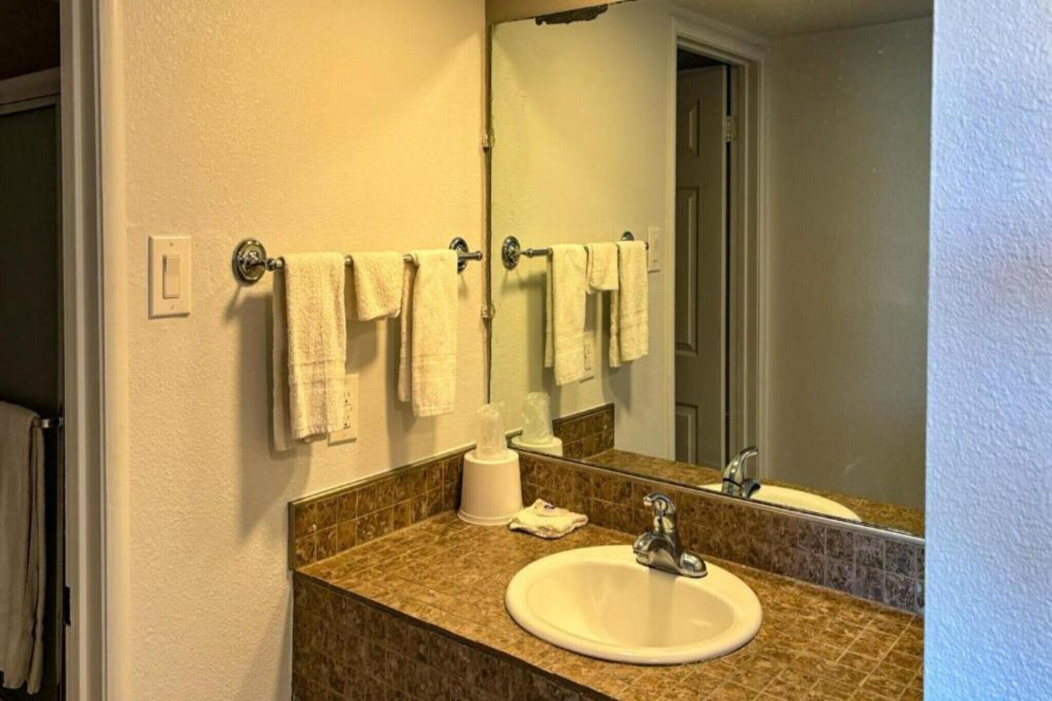 A bathroom with a sink, mirror, towel rack, and a tissue dispenser.