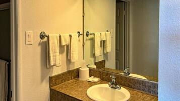 A bathroom with a sink, mirror, towel rack, and a tissue dispenser.