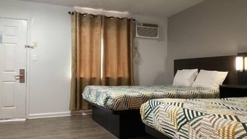 Une chambre avec deux lits, une porte, un appareil de climatisation et un rideau.