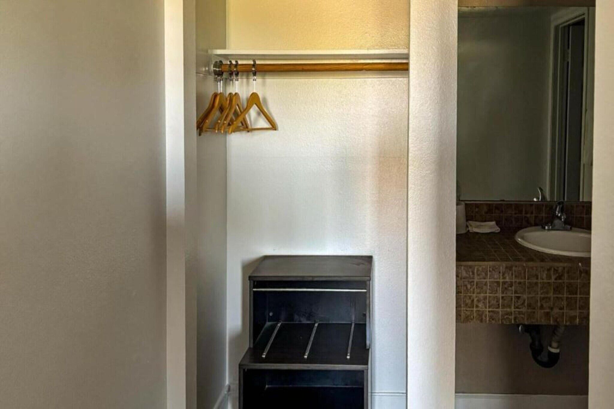 A compact bathroom with a sink, mirror, and towel rack.