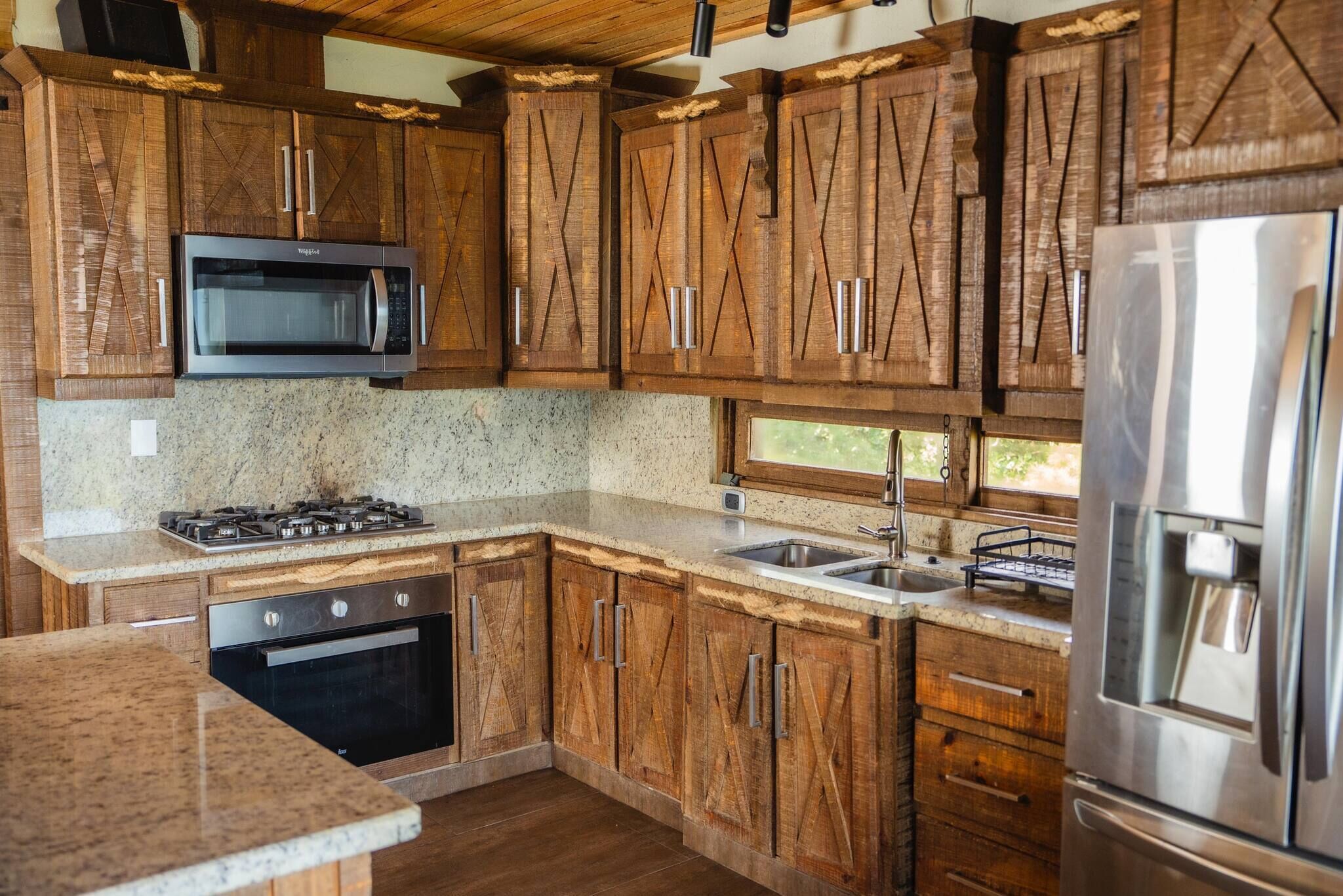 A kitchen with wooden cabinets, a microwave, a stove, a sink, and a refrigerator.