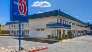 A motel with a 'Motel 6' sign, a 'Welcome' entrance, and a parking lot. - 1 King Bed | Non-Smoking (Grants)