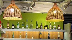 A bar with two hanging lamps, shelves of liquor bottles, and glasses. - The Upperhouse Hotel Boutique Stay with City & River Views (Cagayan de Oro)
