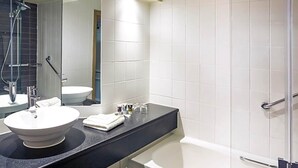 A modern bathroom with a round sink, a bathtub, and a glass shower enclosure.