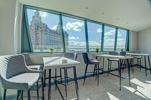 A modern hotel room with large windows, a city view, and a seating area with tables and chairs. - Atlantic Tower Hotel By Sunday - Superior Double Room (Liverpool)
