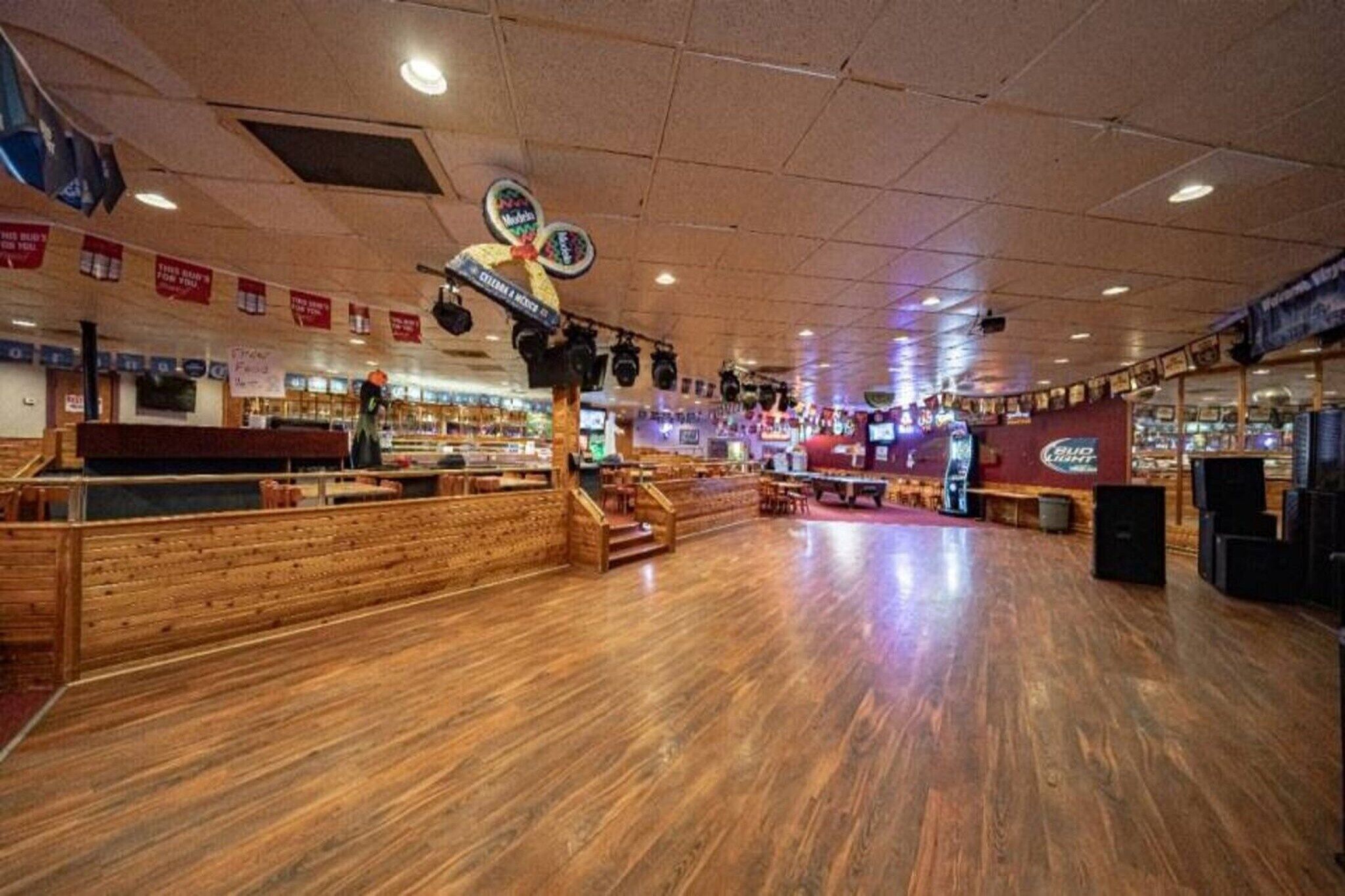 A bowling alley with wooden floors, multiple lanes, and a seating area.