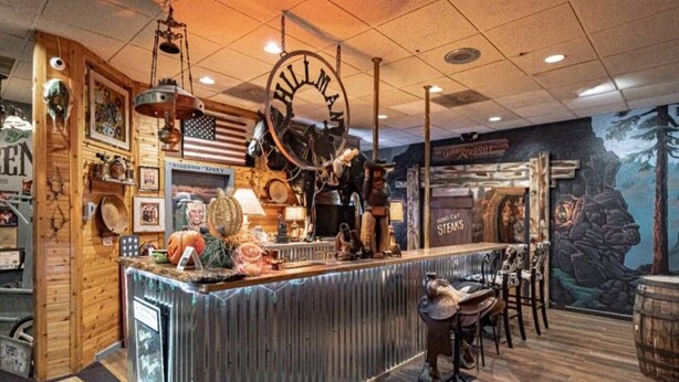A rustic interior with a wooden counter, American flag, and a mural of a bear.