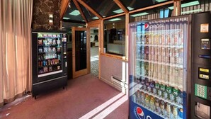 A lobby with a vending machine, a door, and a carpeted floor.