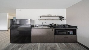 Een kleine keuken met een koelkast, fornuis, magnetron en een klein spoelbakje.
