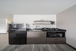 Une cuisine compacte équipée d’un réfrigérateur, d’une cuisinière, d’un four à micro-ondes et d’un petit évier.