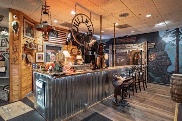 A rustic interior with a wooden counter, American flag, and a mural of a bear.