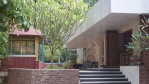 Un edificio con pared de piedra, un árbol y una escalera que lleva a una puerta.