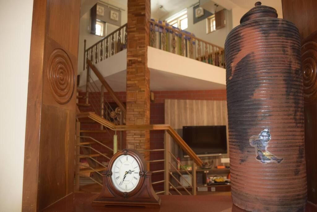 Eine Treppe mit einer Holzhandläufung, einer Uhr und einer großen Vase.