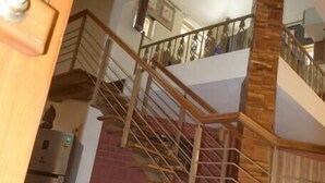 Un interior de varios niveles con una escalera de madera, un refrigerador y un banco con cojines.
