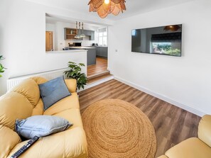 A modern living room with a sofa, a round rug, and a TV mounted on the wall. - Vikings Shore - UK50995 (Broadstairs)