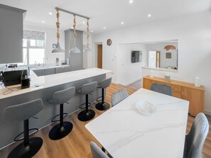 A modern kitchen with a central island, bar stools, a dining table with chairs, and pendant lights. - Vikings Shore - UK50995 (Broadstairs)