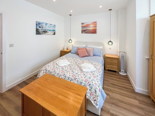 Ein Schlafzimmer mit Bett, Nachttischen, einer Nachttischlampe, einem Heizgerät und Bildern an den Wänden.