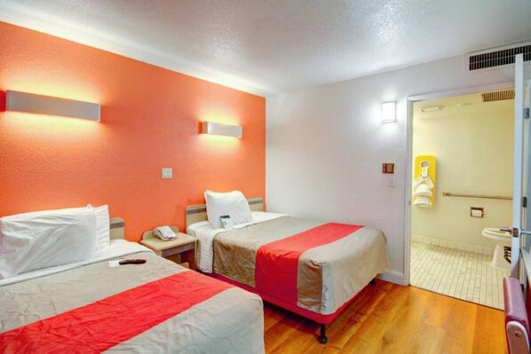 A hotel room with two beds, a bathroom, and a door leading to another room.