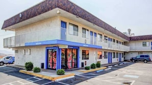 Un motel composé d’un bâtiment à deux étages, d’un parking et d’une enseigne « Bienvenue ».