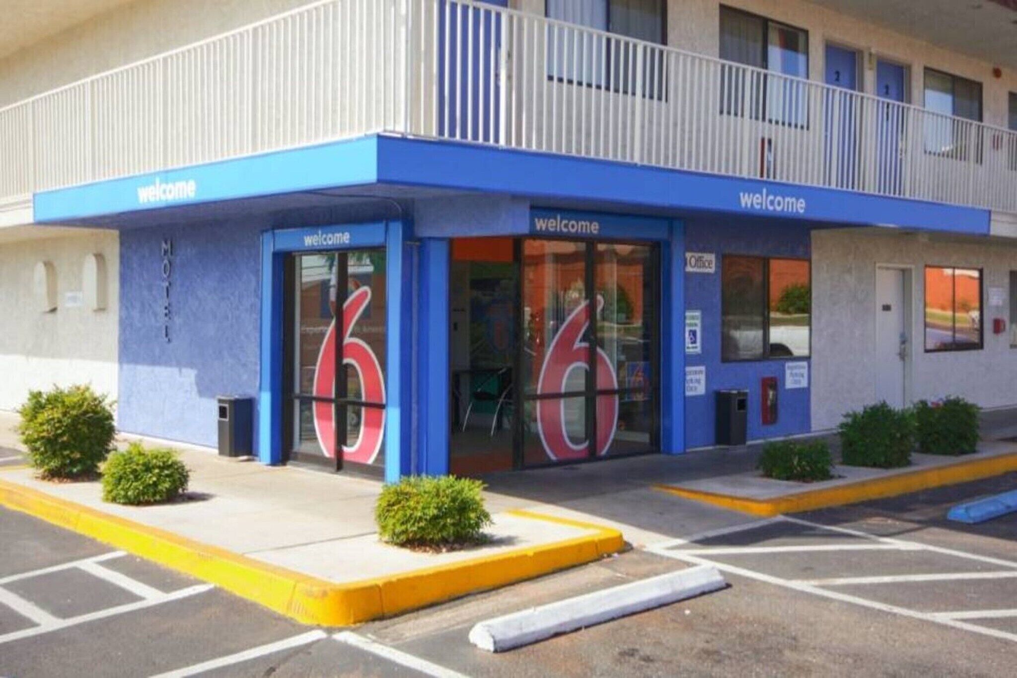 A hotel entrance with a blue facade, large windows, and a 'welcome' sign.