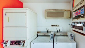 A laundry room with stacked washers and dryers, a wall-mounted air conditioner, and a laundry bar with detergent products. - 2 Full Beds | Smoking (St George UT)