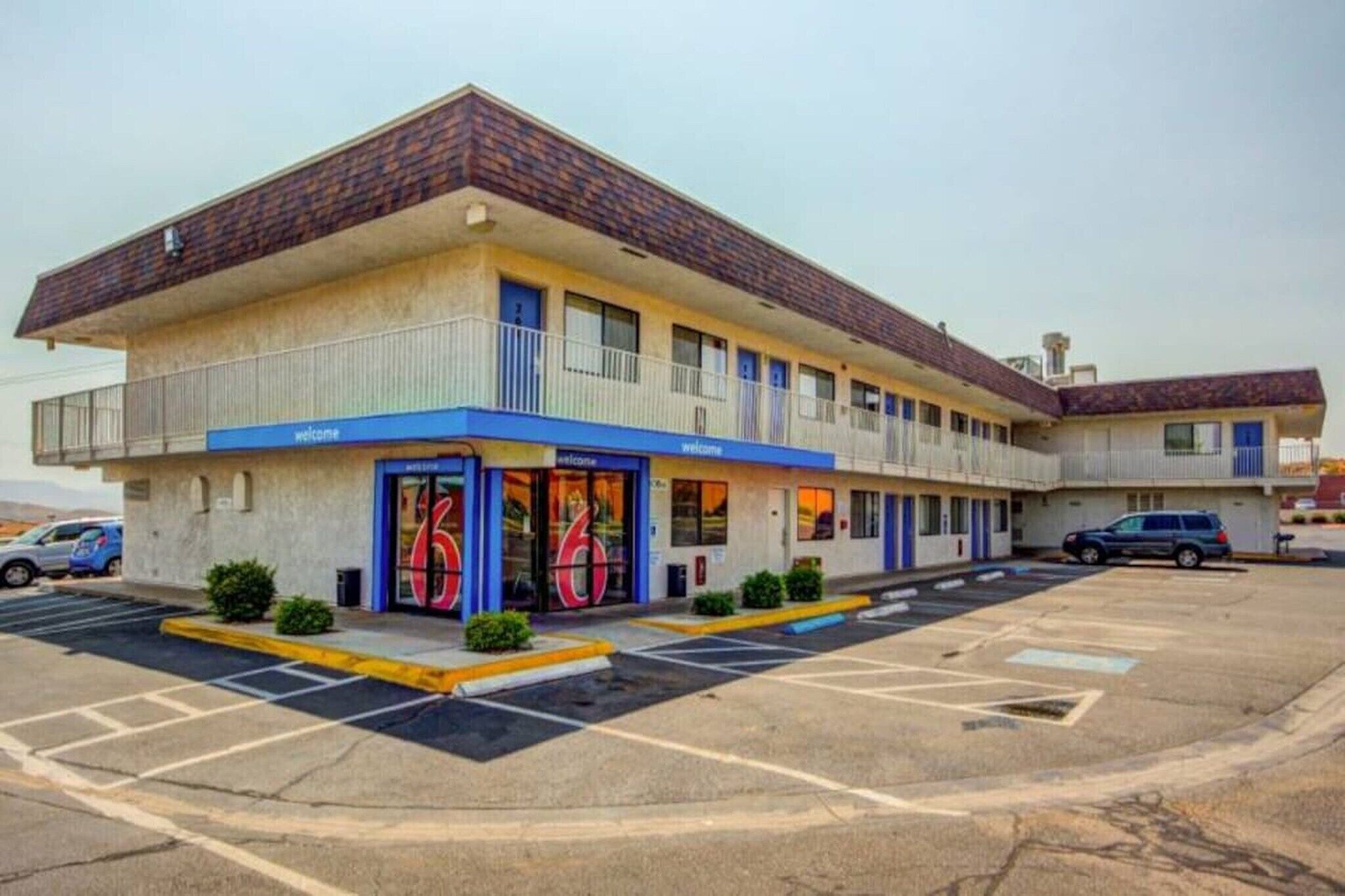 A motel with a two-story structure, a parking lot, and a 'Welcome' sign.