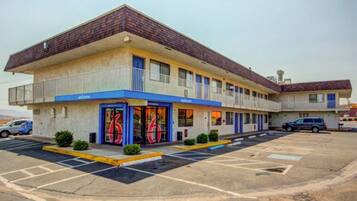 A motel with a two-story structure, a parking lot, and a 'Welcome' sign.