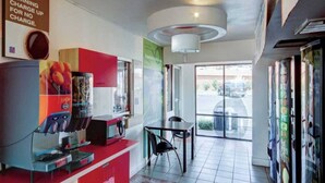 A coffee shop interior with a counter, a juice dispenser, and a table with chairs. - ADA|2 Beds|RI Shower|Nsmk (St George UT)